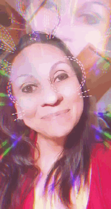 a woman in a red shirt is smiling with a rainbow colored background