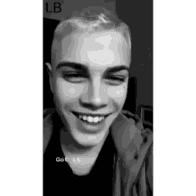 a black and white photo of a young man smiling and looking at the camera .