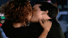 a man and a woman kissing in front of a blurry background