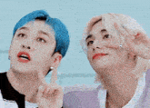 two young men with blue hair are standing next to each other and making a peace sign with their hands .