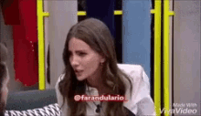 a woman is sitting on a couch talking to another woman in a room .