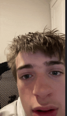 a close up of a young man 's face with a chair behind him