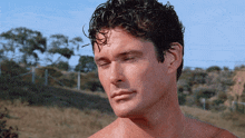 a shirtless man with his eyes closed looks down at something