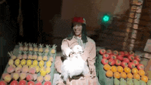 a statue of a man holding a white rabbit in front of a fruit stand