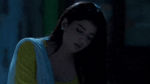 a woman in a yellow top and white shawl is looking at the camera