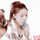 a girl with a ponytail is eating a blue item with the word blur on it