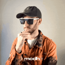 a man wearing sunglasses and a hat with the word mcdh on the bottom right