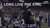a football player is standing on a field with the words `` long live the king '' on the screen .