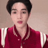 a close up of a young man wearing a red jacket and looking at the camera .