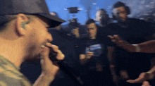 a man wearing a hat with the letter t on it sings into a microphone