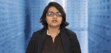 a woman wearing glasses and a suit is making a face .