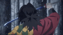a man in a red jacket is holding a sword in a forest .