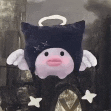 a stuffed animal with wings and a halo on its head is wearing a black hat .