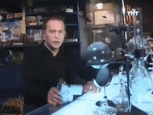 a man standing in front of a microscope with the word tht on the top right