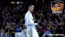 a soccer player celebrates a goal in front of a crowd with a make a gif.com watermark