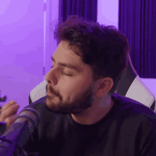 a man with a beard is sitting in a chair in front of a microphone with his eyes closed