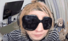 a woman wearing a striped shirt and sunglasses makes a funny face