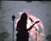 a woman with long hair is playing a guitar in front of a microphone