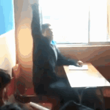 a man sitting at a desk with his arm up