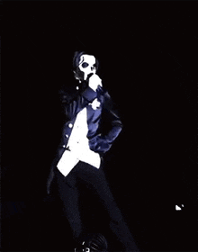 a man in a skeleton costume is holding a microphone on a stage .