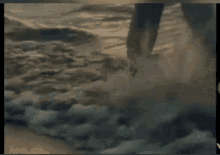 a person 's feet are visible in the water in a blurry photo