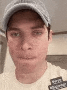 a man wearing a hat and a white t-shirt is making a funny face .