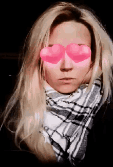 a woman wearing a plaid scarf and pink heart shaped glasses
