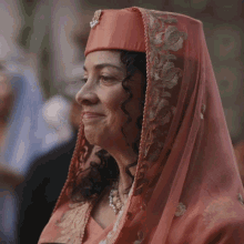 a woman wearing a veil and a hat smiles for the camera