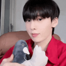 a young man in a red shirt is holding a stuffed animal in his hands .