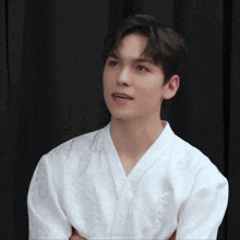 a young man wearing a white shirt with a black curtain behind him and the words yemonisource on the bottom left