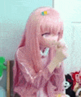 a doll with pink hair is wearing a pink sweater and gloves .