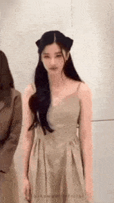 a woman in a dress with a cat ear on her head is standing in front of a wall .