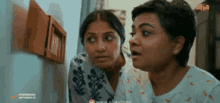 two women are looking at something in a room with the website www.abha.com on the bottom