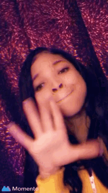 a young girl is waving her hand at the camera .