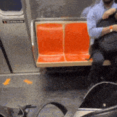 a man sits on a train with a do not lean on door sign above him