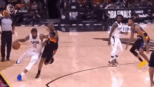 a group of basketball players are playing a game of basketball on a court with a referee .