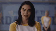 a woman wearing a yellow shirt and a pearl necklace