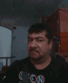 a man with a beard is wearing a black shirt with the letters len on it .