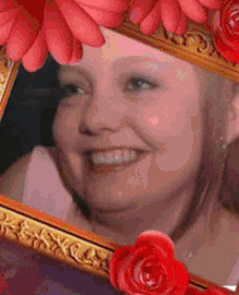 a picture of a smiling woman in a gold frame with red roses