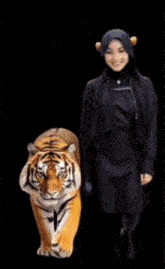 a woman in a hijab stands next to a stuffed tiger holding a fireball