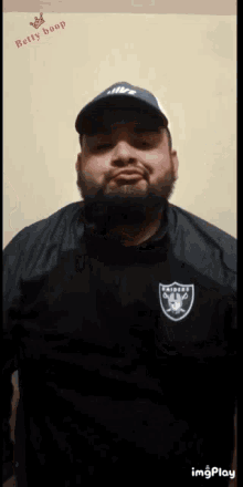 a man with a beard wearing a raiders jacket and hat