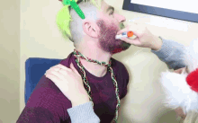 a man with a green mohawk is being painted red by another person