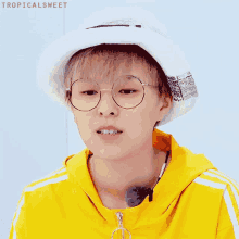 a young boy wearing glasses and a hat with tropicalsweet written on the bottom right