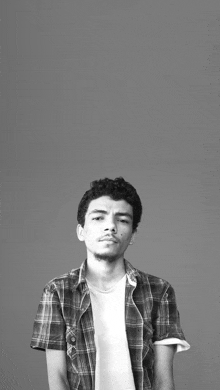 a black and white photo of a young man wearing a plaid shirt and white shirt