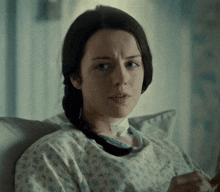 a woman in a hospital gown is sitting in a bed