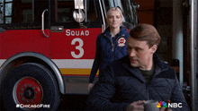 a man and a woman are standing in front of a fire truck with the number 3 on it