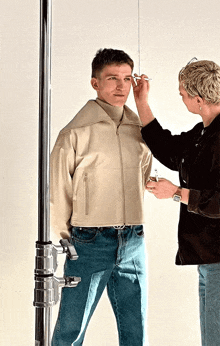 a woman applies makeup to a man 's face