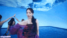 a woman in a purple dress is giving a high five in a room with a blue ceiling