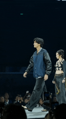 a man in a blue jacket is walking down a stage