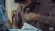 a man is sitting at a table eating a piece of food from a box .